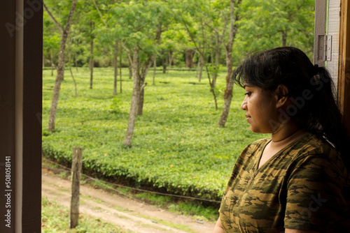 A beautiful Indian female traveler enjoying the beauty of tea garden from the window. photo