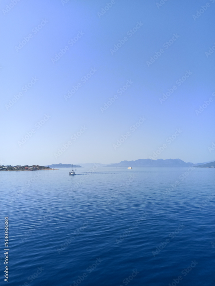 Landscape of the sea and an island with mountains and boats on the water. Beautiful summer photo