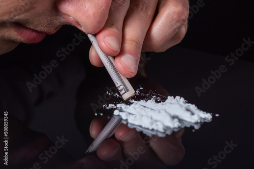 Concept drug addiction.. Drug abuse, man taking drugs, snorting lines of cocaine powder, close up photo