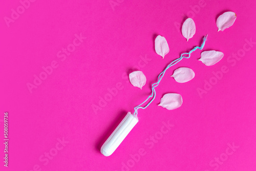 Female tampon with with cherry petals on a pink background. Hygienic white tampon for women. Cotton swab.