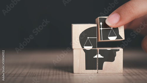 Ethics inside human mind, Business ethics concept. Hand hold ethics inside a head symbols in wooden cubes on dark background with copy space. photo
