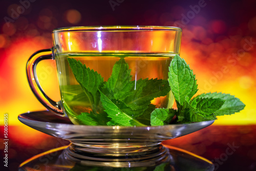 Cups of tea with fresh mint on multicolored background