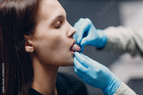 Young woman doing tonque piercing at beauty studio salon