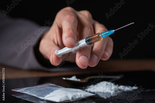 Drug syringe in hand. A drug addict with another dose of the drug in the syringe. Guy addicted