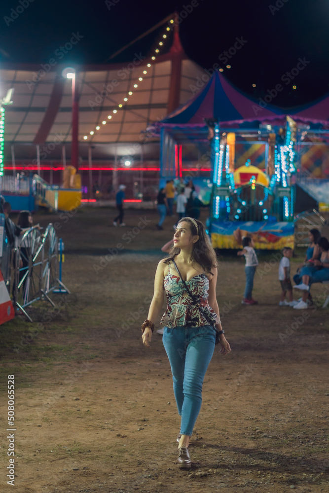 AMUSEMENT PARK FULL OF LIGHTS AND COLOR WITH MECHANICAL ATTRACTIONS WOMAN ENJOYING THE PLACE