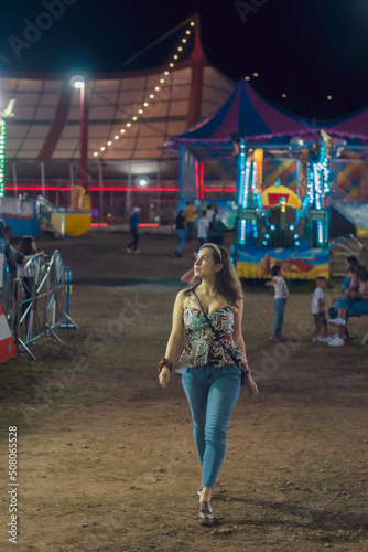 AMUSEMENT PARK FULL OF LIGHTS AND COLOR WITH MECHANICAL ATTRACTIONS WOMAN ENJOYING THE PLACE © elking