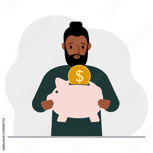 Sad man holds a piggy bank, a coin falls into the piggy bank. The concept of saving finance, savings, investing finances.