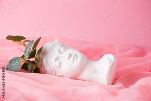 Bust of a Greek goddess on a pastel pink background. Minimal flat still life. Beauty overhead concept.