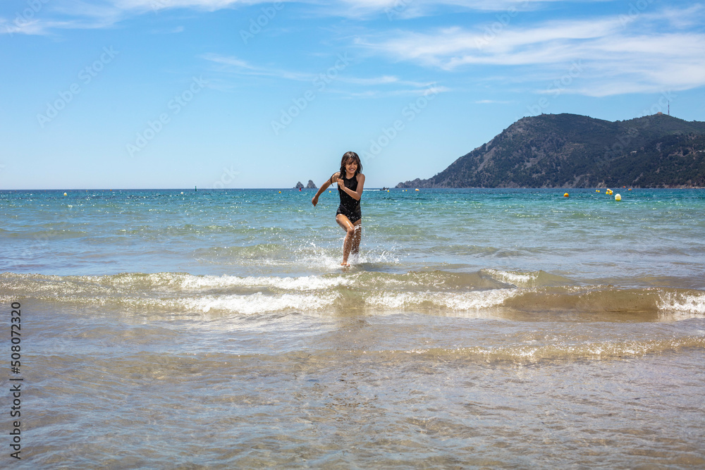 Une jolie jeune fille asiatique court heureuse dans l'eau sur la plage Une jolie jeune fille asiatique court heureuse dans l'eau sur la plage