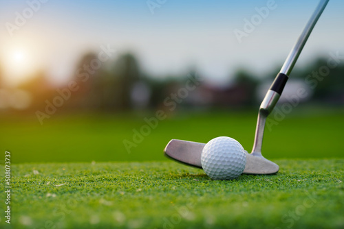 Golf clubs and golf balls on a green lawn in a beautiful golf course with morning sunshine.