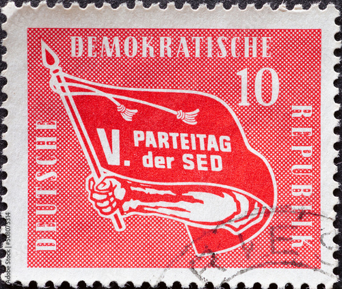 GERMANY, DDR - CIRCA 1958 : a postage stamp from GERMANY, DDR, showing a red flag as an emblem of the V. Congress of the Socialist Unity Party of Germany. Circa 1958 photo