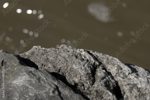Close up of textured rocks against a high bokeh river.