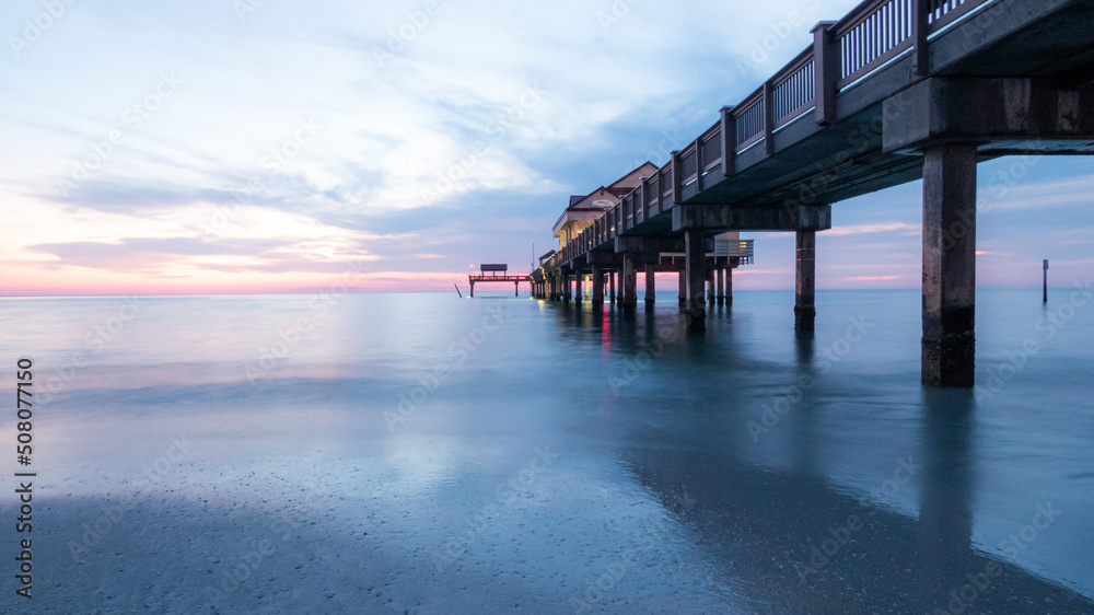 Pier at sunset on the beautiful silky waters on Clearwater beach in Florida.