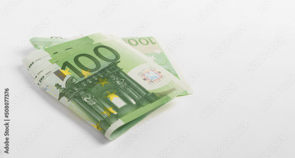 Green banknotes of one hundred euros on a light background.