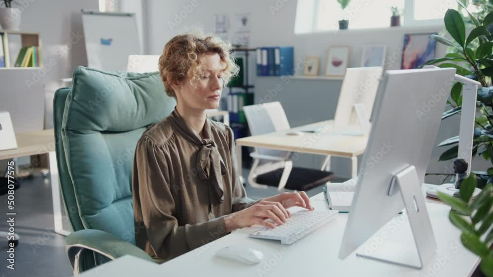 Serious businesswoman working use computer typing on keyboard in the office. Look at the screen. Sunlight in modern office Serious businesswoman working use computer typing on keyboard in the office. Look at the screen. Sunlight in modern office