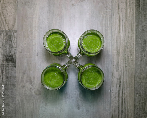 Top view of four mason jars with green smoothies. Healthy eating, make ahead concept.