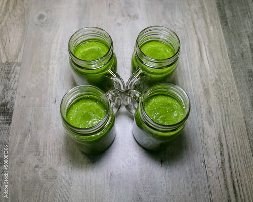 Four mason jar glasses with handles  with alkaline green drinks.