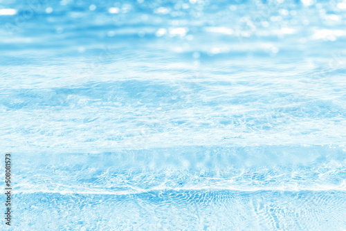 blue refreshing water waves in sunshine, sun reflections on beautiful empty blurred water background, concept with copy space for cosmetics, beach vacations, sustainable water resources