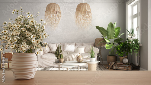 Wooden table top or shelf with pottery vase with daisies, wild flowers, over scandinavian living room with white sofa, pendant lamp and carpet, minimalist interior design concept