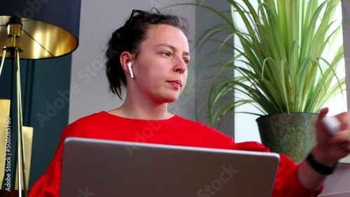 Young woman putting on ears wireless bluetooth headphones before laptop computer working, sitting in modern interior.Freelancer prepare before online conference distance office chat, virtual training photo