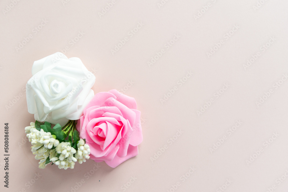 White and pink roses with white little flowers on a pale pink background with space for text White and pink roses with white little flowers on a pale pink background with space for text
