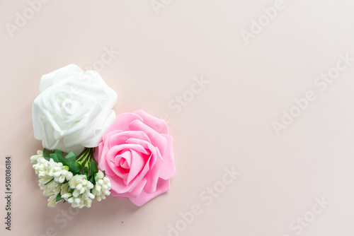 White and pink roses with white little flowers on a pale pink background with space for text