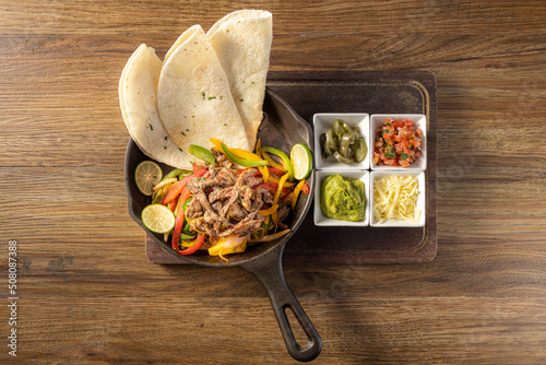 Mexican Beef fajita with bell peppers, grilled vegetables and onions top view on dark wooden background photo