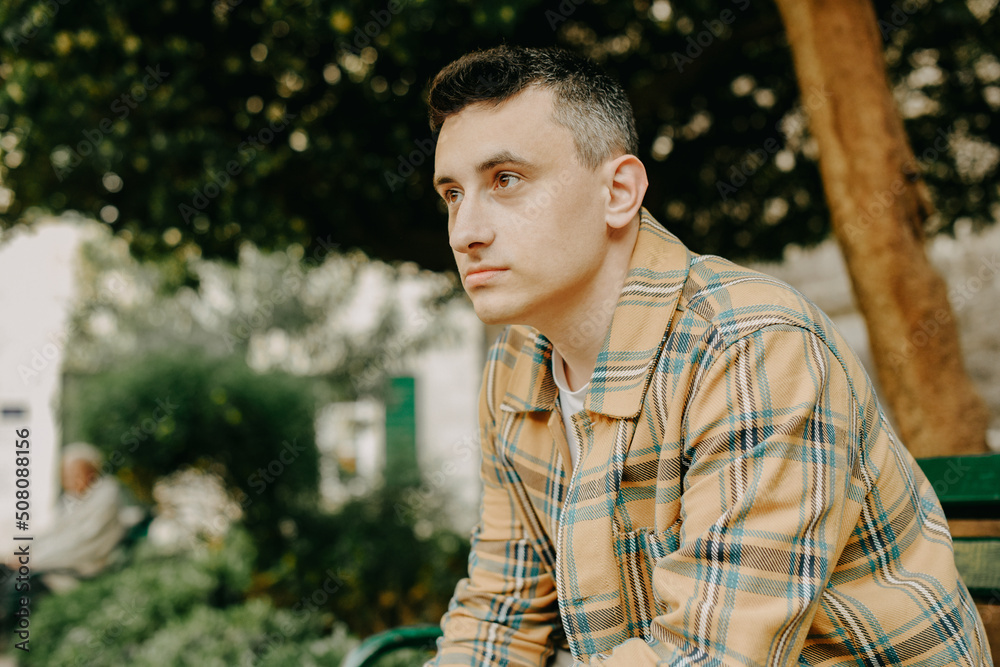 A man sits on a bench and looks ahead. male portrait. A man sits on a bench and looks ahead. male portrait.