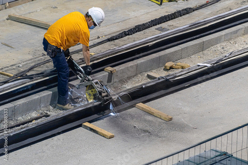 Heavy industry worker cutting steel Light rail with an angle grinder in workshop. High quality photo
