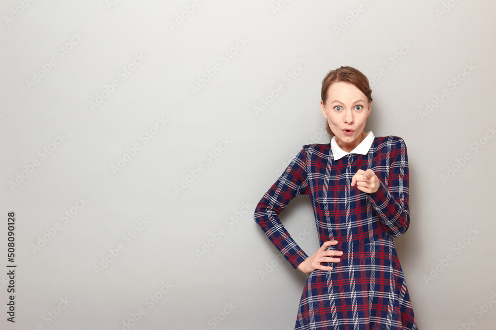 Portrait of amazed young woman pointing with index finger at you Portrait of amazed young woman pointing with index finger at you
