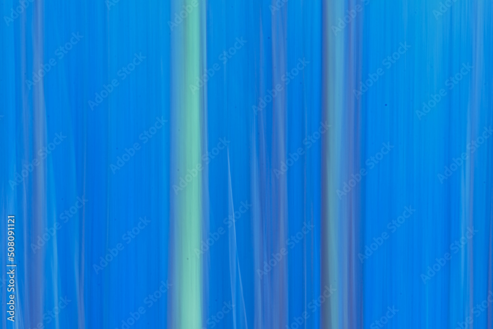 Abstract background through intentional camera movement of tree trunks tints of blue . vertical texture 