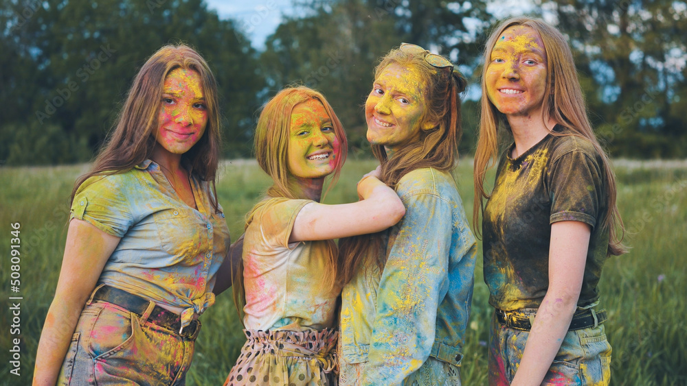 Fototapeta premium Cheerful girls posing smeared in multi-colored powder.