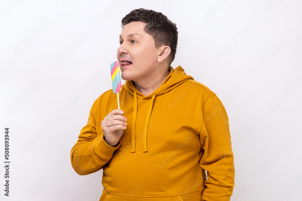 Funny man sticking out tongue licking ice cream, tasting and enjoying delicious flavor dessert, sweet confection, wearing urban style hoodie. Indoor studio shot isolated on white background. Funny man sticking out tongue licking ice cream, tasting and enjoying delicious flavor dessert, sweet confection, wearing urban style hoodie. Indoor studio shot isolated on white background.