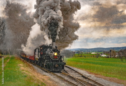 An Antique Steam Passenger Train Traveling Thru Farmlands Puffing Lots of Smoke on a Cloudy Winter Day