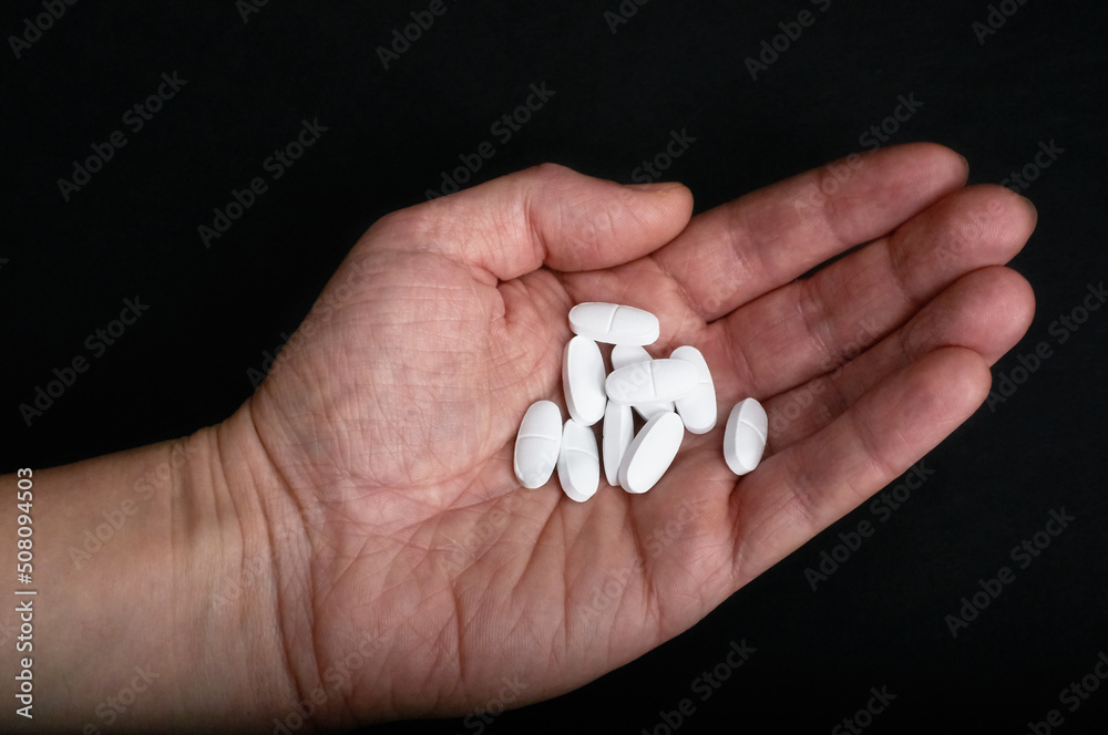 a pile of pills lies in a hand on a black background a pile of pills lies in a hand on a black background