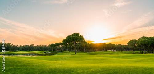 Scenic panoramic view of Golf course at sunset with beautiful sky. Golf fairway with pines