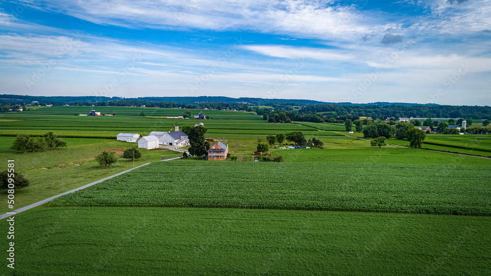 Aerial View of Farmlands With Barns and Silos, Looking Over the Hills and Fields of Rich Crops Growing on a Sunny Summer Day Aerial View of Farmlands With Barns and Silos, Looking Over the Hills and Fields of Rich Crops Growing on a Sunny Summer Day