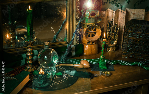 Illustration of magical stuff....candle light, Chrystal ball, magic wand, book of spells dark background, Slytherin school, green aesthetic, Halloween time photo