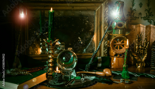 Illustration of magical stuff....candle light, Chrystal ball, magic wand, book of spells dark background, Slytherin school, green aesthetic, Halloween time photo