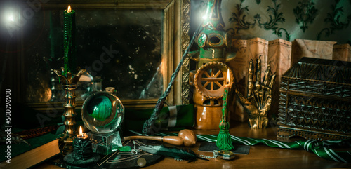 Illustration of magical stuff....candle light, Chrystal ball, magic wand, book of spells dark background, Slytherin school, green aesthetic, Halloween time photo