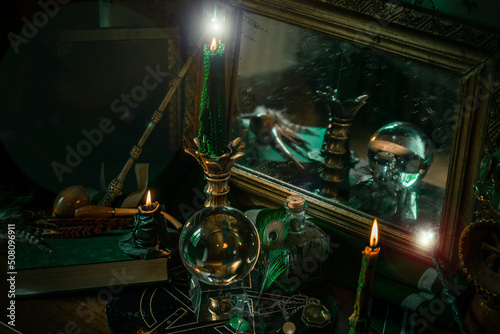 Illustration of magical stuff....candle light, Chrystal ball, magic wand, book of spells dark background, Slytherin school, green aesthetic, Halloween time