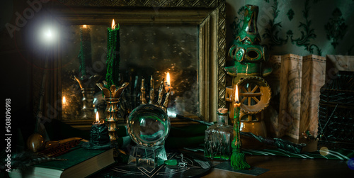 Illustration of magical stuff....candle light, Chrystal ball, magic wand, book of spells dark background, Slytherin school, green aesthetic, Halloween time photo
