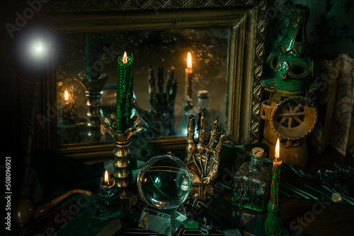 Illustration of magical stuff....candle light, Chrystal ball, magic wand, book of spells dark background, Slytherin school, green aesthetic, Halloween time photo