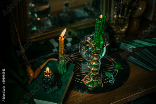 Illustration of magical stuff....candle light, Chrystal ball, magic wand, book of spells dark background, Slytherin school, green aesthetic, Halloween time photo