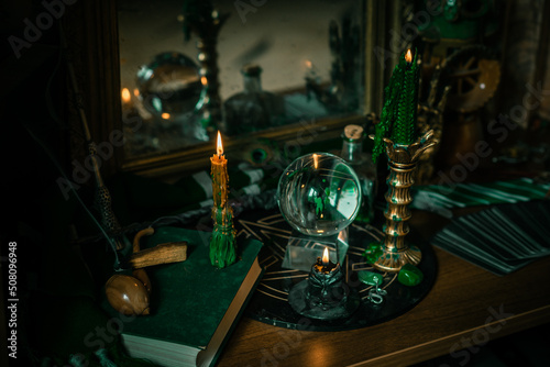 Illustration of magical stuff....candle light, Chrystal ball, magic wand, book of spells dark background, Slytherin school, green aesthetic, Halloween time photo