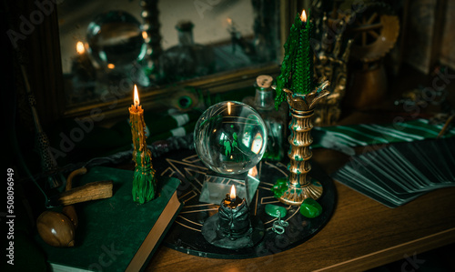 Illustration of magical stuff....candle light, Chrystal ball, magic wand, book of spells dark background, Slytherin school, green aesthetic, Halloween time photo