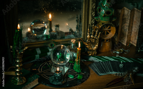 Illustration of magical stuff....candle light, Chrystal ball, magic wand, book of spells dark background, Slytherin school, green aesthetic, Halloween time photo