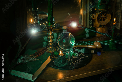 Illustration of magical stuff....candle light, Chrystal ball, magic wand, book of spells dark background, Slytherin school, green aesthetic, Halloween time photo