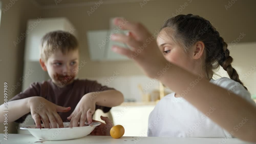 Boy and girl rides cocoa chocolate. Sweet breakfast at table in the kitchen. Dirty face of child. Happy family concept. Cheerful hungry children eat chocolate. Child eat chocolate sitting at table Boy and girl rides cocoa chocolate. Sweet breakfast at table in the kitchen. Dirty face of child. Happy family concept. Cheerful hungry children eat chocolate. Child eat chocolate sitting at table