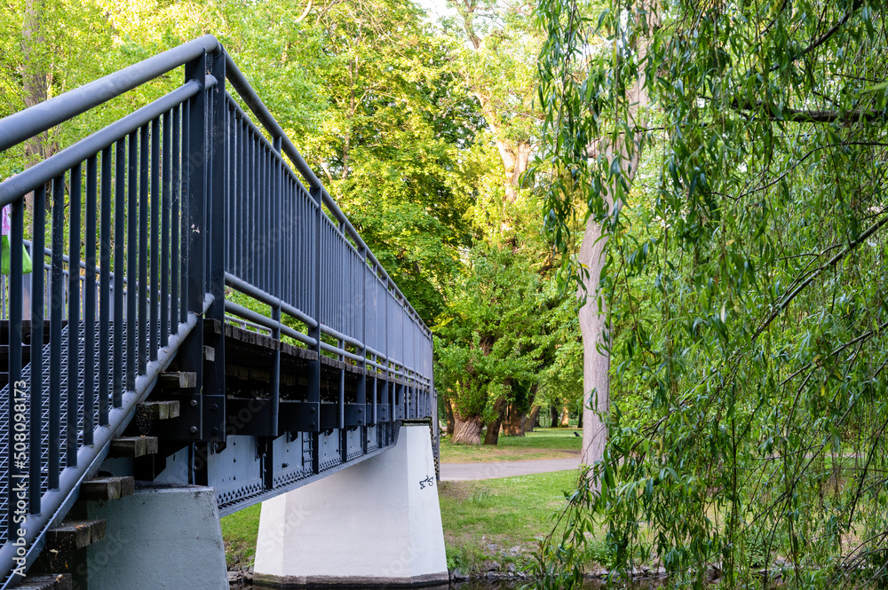 Footbridge over a river in the park on a sunny day in spring. Footbridge over a river in the park on a sunny day in spring.